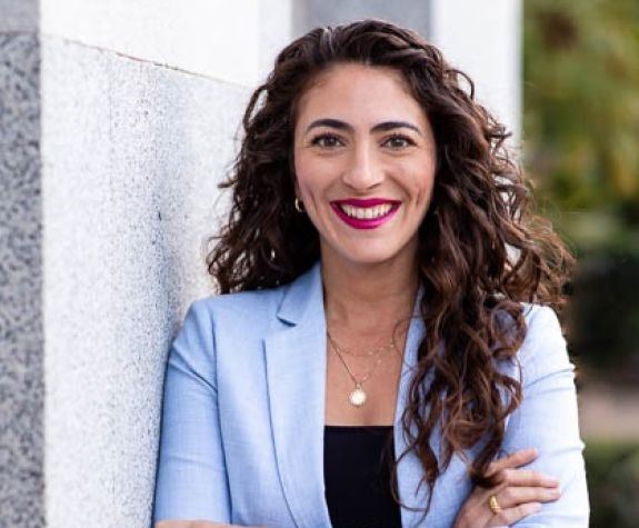 A woman wearing a suit smiles for a photo outside
